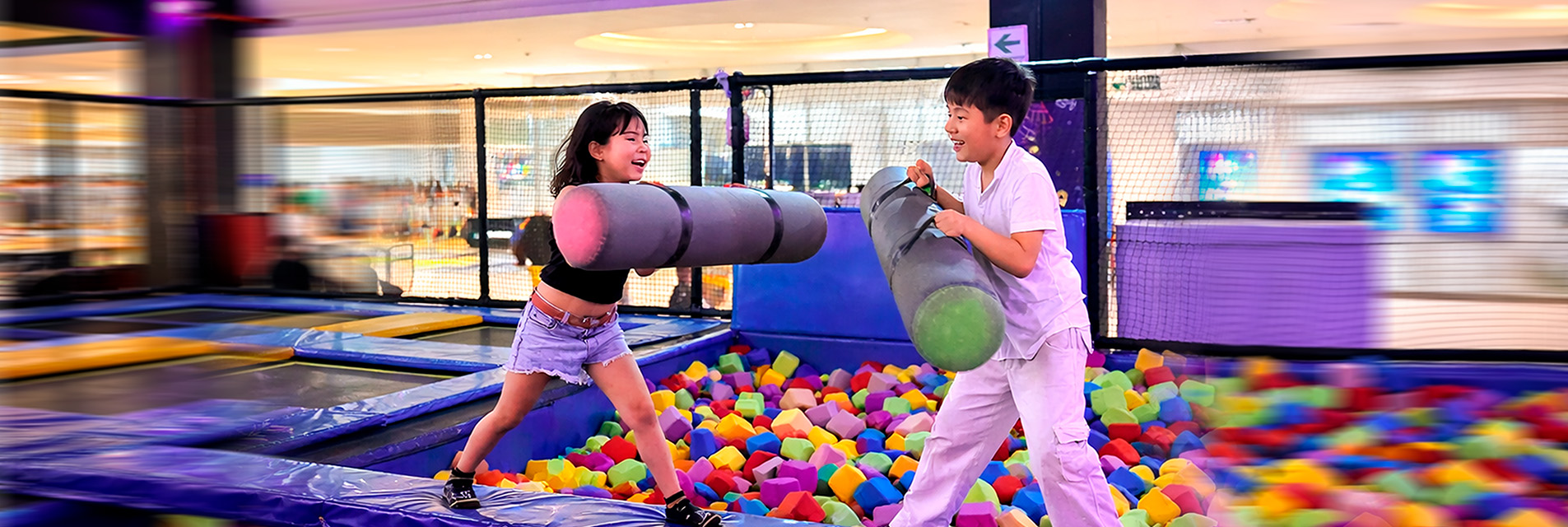 Niños en palestra de lucha sobre piscina de espumas, diversión segura en todas las sedes